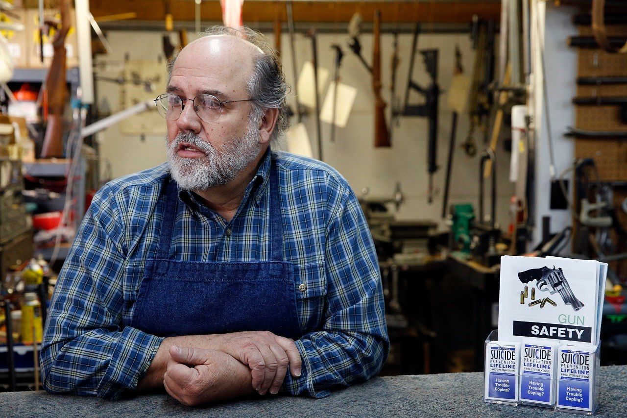 In this Feb. 23, 2016 photo, expert gunsmith Keith Carey stands behind the counter at his shop, where he makes suicide prevention literature available, in Montrose Colo. Carey is a staunch, though soft-spoken, defender of the right to bear arms.