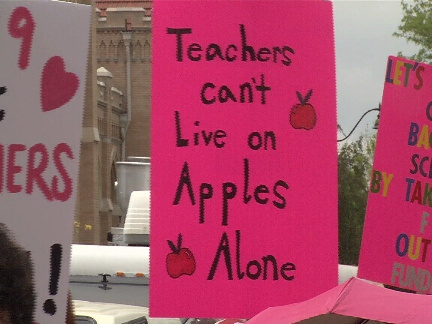 A sign held by striking teachers in Pueblo reads 'Teachers can't live on apples alone"